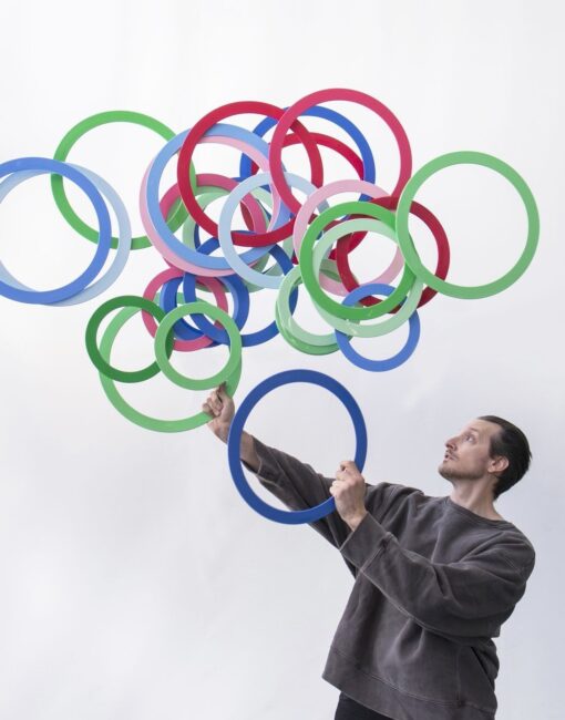 Jonglööri Jay Gilligan heittää valtavan määrän värikkäitä renkaita ilmaan.