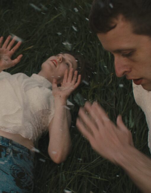 Nuori nainen ja mies makaavat nurmella. Sataa lunta.