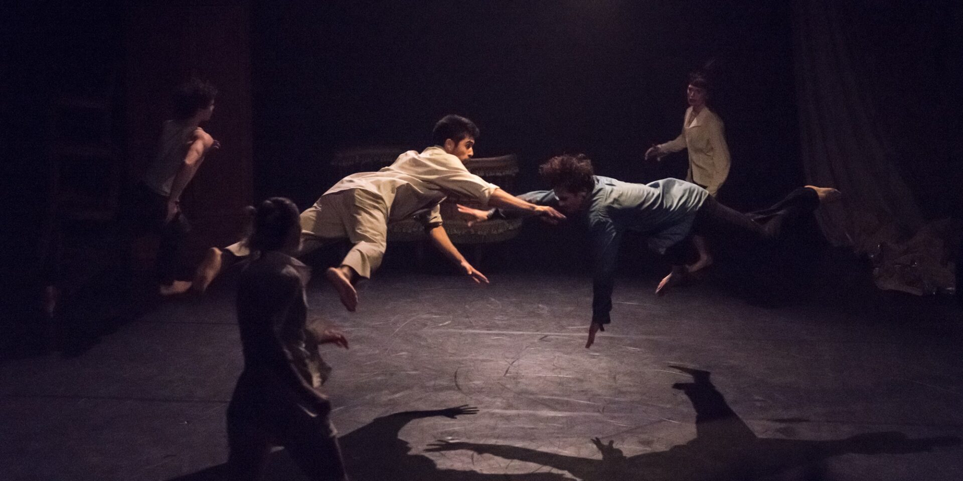 Kaksi ihmistä lentää vatsallaan ilmassa. Neljä ihmistä katselee ympärillä.